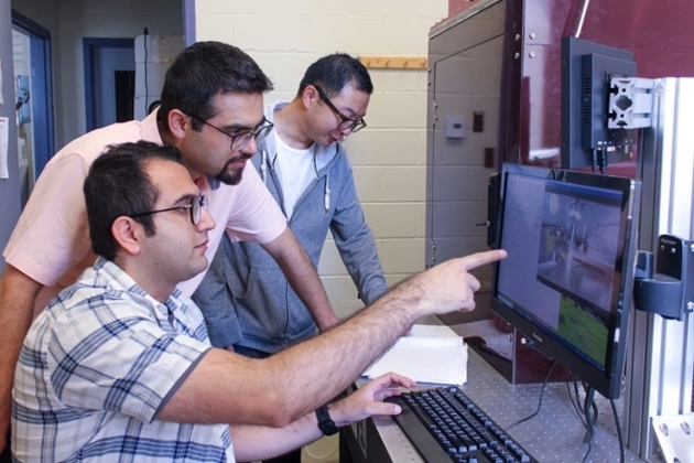three male researchers looking at a screen in a lab