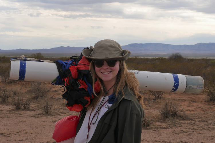 Abby Lee smiles holding a rocket over her shoulder