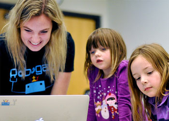  A woman with two children smiling in front of a computer